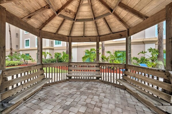 A covered outdoor area with a wooden bench and a brick floor, surrounded by a wooden railing. - Suites at Lake Buena Vista close Disney Spring (Orlando)