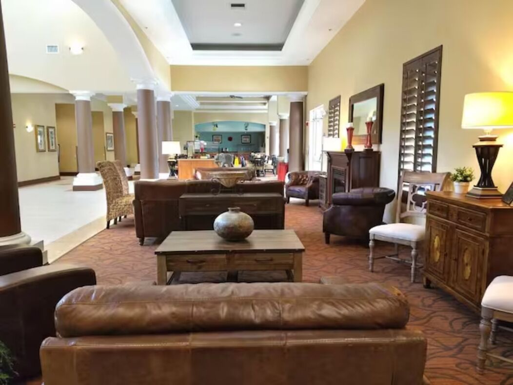 A spacious lobby with leather sofas, a coffee table, and a fireplace.
