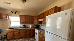 Una cocina con armarios de madera, un refrigerador blanco, una estufa y un lavabo.