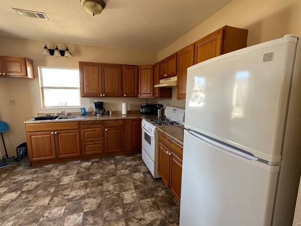 A kitchen with wooden cabinets, a white refrigerator, a stove, and a sink.