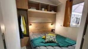 A compact bedroom with a bed, built-in shelves, a window, and a door. - ZEcamping familial avec piscine - proche Oléron (La Tremblade)