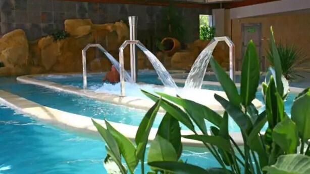 An indoor swimming pool with a waterfall feature, surrounded by rocks and plants. - ZEcamping 5 étoiles pet friendly animé avec piscine couverte en bord de mer (Saint-Georges-d'Oléron)