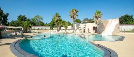 A swimming pool with a curved edge, surrounded by lounge chairs and palm trees.