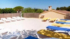 Un espace piscine avec des chaises longues et un petit bâtiment en arrière-plan.