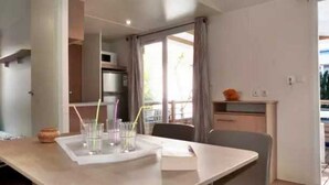 Un espace repas moderne avec une table dressée pour deux personnes, un four à micro-ondes et un petit coin cuisine.