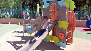 Un enfant joue sur une structure de jeux d’enfants comprenant un toboggan et des éléments d’escalade.