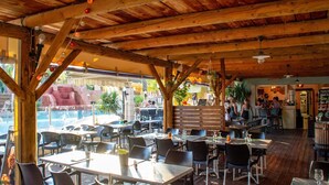 Un restaurant en plein air avec des poutres, des tables et des chaises en bois.