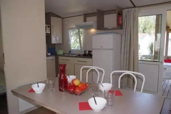 A compact kitchen with a dining table set for two, a refrigerator, and a window providing natural light.