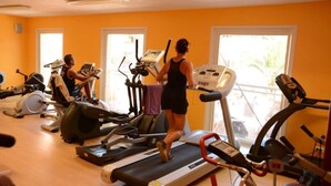 Un gimnasio con cintas de correr, bicicletas estáticas y elípticas.