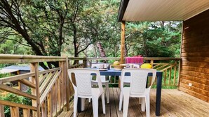 A wooden deck with a table and chairs, surrounded by trees.