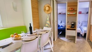 Una habitación compacta con mesa, sillas, pequeña cocina y cama.