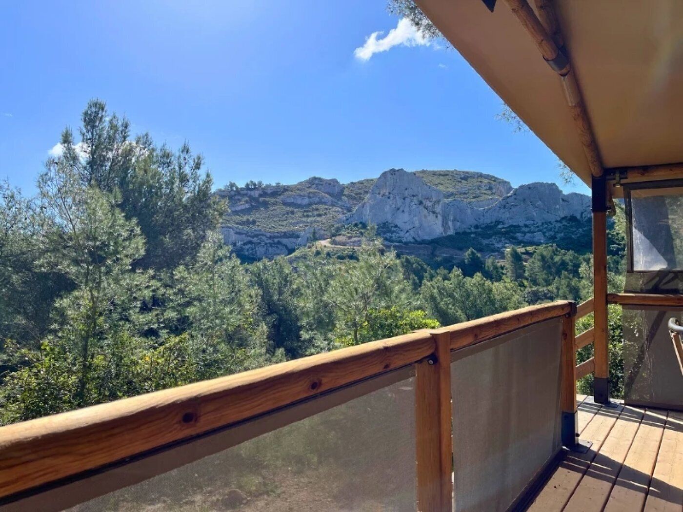 A wooden deck with a view of rocky mountains and dense greenery.