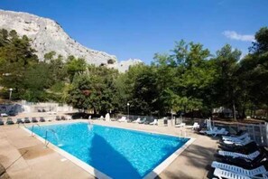 Relax by the pool surrounded by lush trees and a breathtaking mountain view.