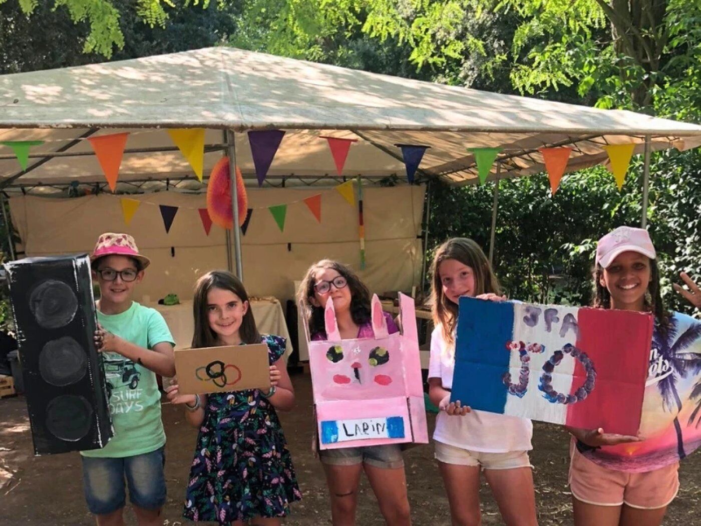 A group of people holding signs under a tent with colorful flags.
