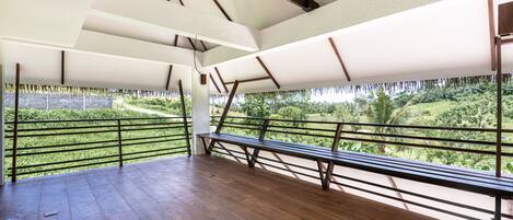 An open-air pavilion with a wooden bench and a view of a lush green landscape.