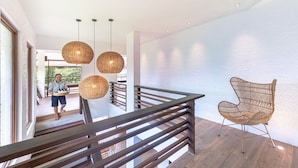 A modern interior with a wooden staircase, wicker pendant lights, and a woven chair. - La Fuga Siargao (General Luna)