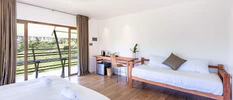 A hotel room with two beds, a desk, and a large window with curtains.