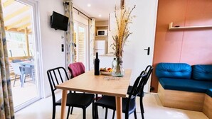 Un comedor con mesa de madera, sillas negras y un florero con plantas secas.
