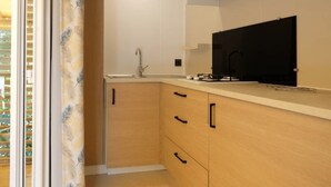 Eine moderne Küche mit Holzausstattung, einem schwarzen Herd und einem großen Fenster mit Jalousien.