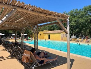 Uma área de piscina com espreguiçadeiras e uma pérgola de madeira.