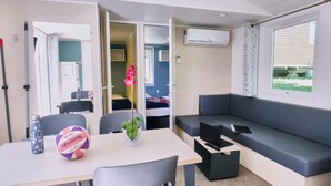 A compact living space with a dining table, chairs, a sofa, and a small kitchen area.