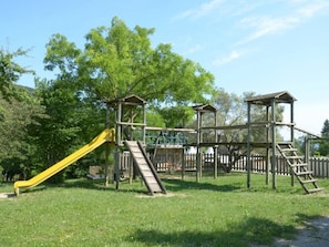 A playground with a slide, climbing structures, and a fenced area.