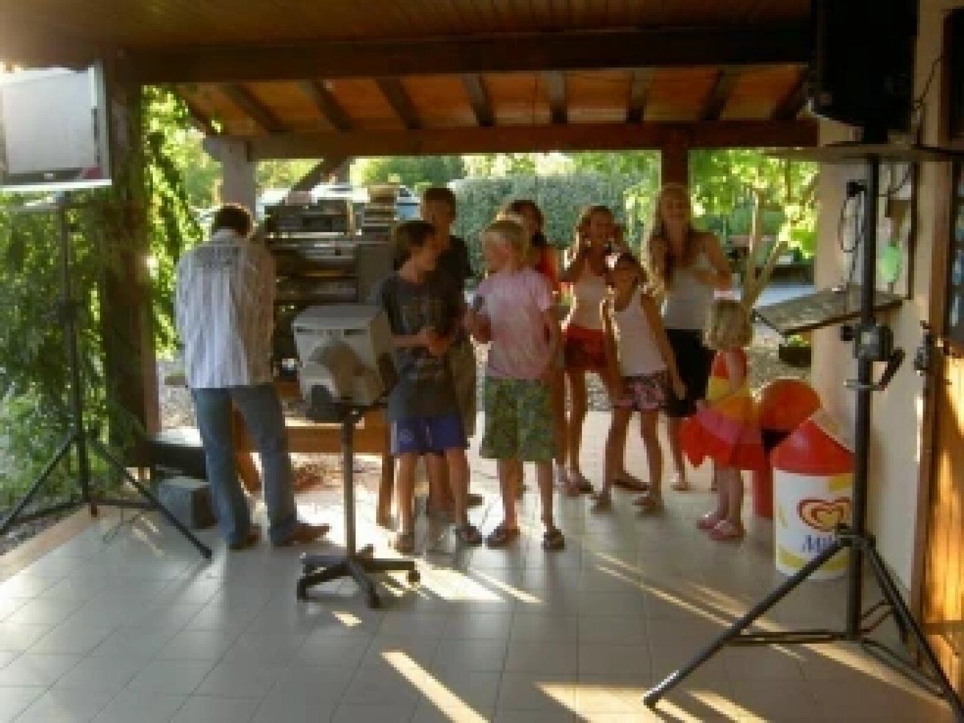 A covered outdoor area with a group of people, a grill, and a tent.