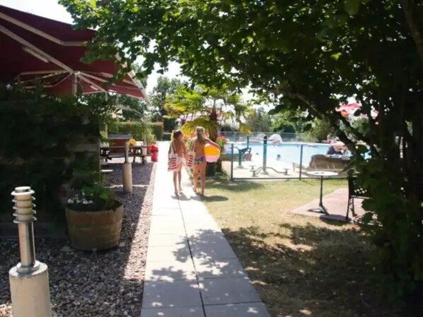 A pathway leading to a pool area with a covered seating area and potted plants.