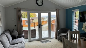 A modern living room with a grey sofa, a wooden coffee table, and a TV on a blue wall. - V+B's Hygge, Gorgeous Lake View at V&B Hygge (Troutbeck Bridge)