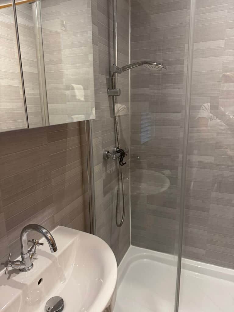 A bathroom with a glass shower enclosure, a white sink, and a bathtub.