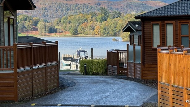 A gravel pathway leading to a wooden cabin with a view of a lake and mountains in the distance. - V+B's Hygge, Gorgeous Lake View at V&B Hygge (Troutbeck Bridge)