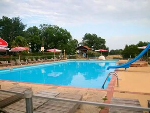 Piscina com espreguiçadeiras e guarda-sóis.