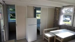 Habitació senzilla amb cuineta, zona de menjador amb taula i cadires, i finestra que dona a l'exterior.