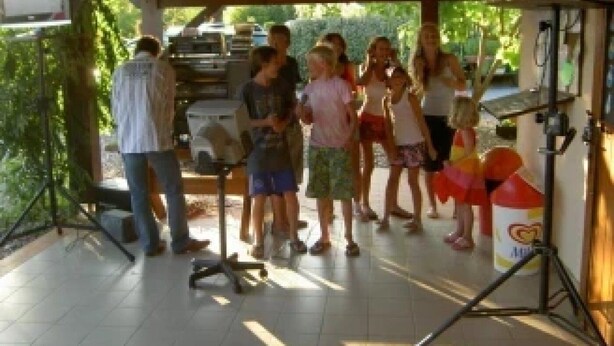 A covered outdoor area with a group of people, a grill, and a tent.