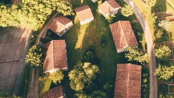 Une vue aérienne d’un quartier résidentiel où les maisons sont disposées en cercle, entourées d’arbres et surplombées par un ciel dégagé.
