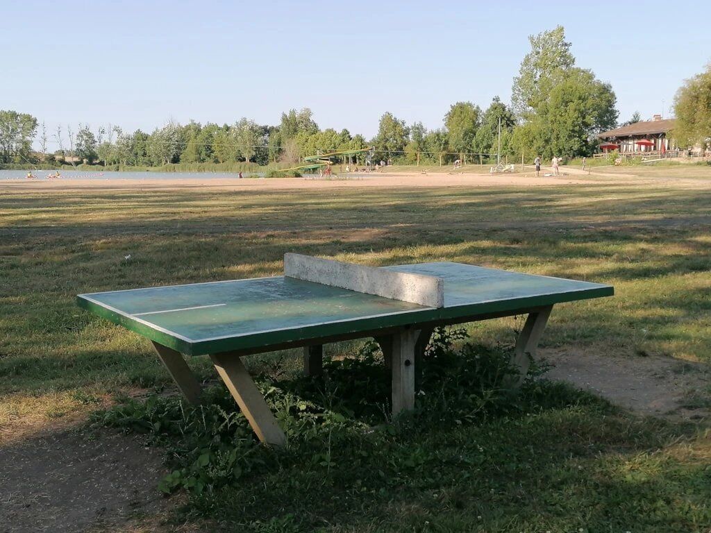 Un parc avec une table de ping-pong verte en premier plan.