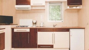 A compact kitchen with wooden cabinets, a built-in stove, a sink, and a window with blinds.