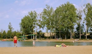 A lakeside park with a playground, picnic areas, and people relaxing by the water.