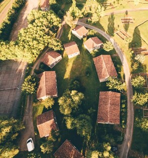 Vista aérea de una zona residencial con casas dispuestas en un patrón circular, rodeada de árboles y un cielo despejado.