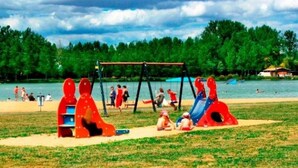 A playground with swings and slides near a body of water. - ZEcamping 3 étoiles parc aquatique chiens acceptés locatif TV LV 75m2 (Moncontour)