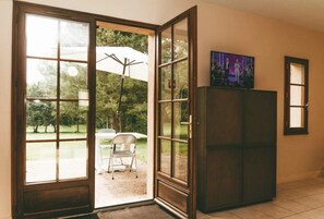 Una habitación con puerta corredera de vidrio que da a un patio con mesa y sillas, refrigerador y un cuadro en la pared.