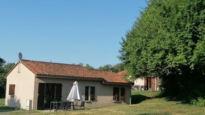 A small building with a tiled roof, a satellite dish, and a covered outdoor seating area with chairs and a table. - ZEcamping 3 étoiles parc aquatique chiens acceptés locatif TV LV 75m2 (Moncontour)