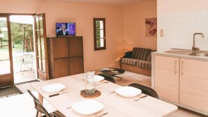 A modern kitchen with a dining table set for four, a sofa, and a TV on a cabinet. - ZEcamping 3 étoiles parc aquatique chiens acceptés locatif TV LV 75m2 (Moncontour)