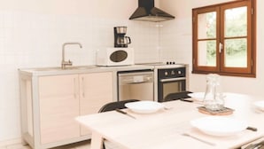 A compact kitchen with a sink, microwave, stove, and a window with a view of greenery. - ZEcamping 3 étoiles parc aquatique chiens acceptés locatif TV LV 75m2 (Moncontour)