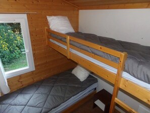 Dormitorio con literas y ventana que da a vistas de vegetación.