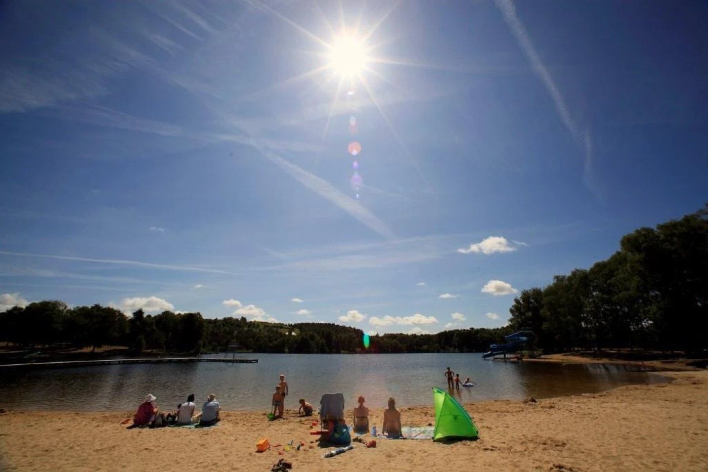 Ein Strand mit entspannten Menschen, ein See und ein klarer Himmel.