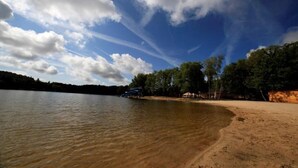 Une vue sur le lac, avec une plage de sable, des arbres et un ciel dégagé.