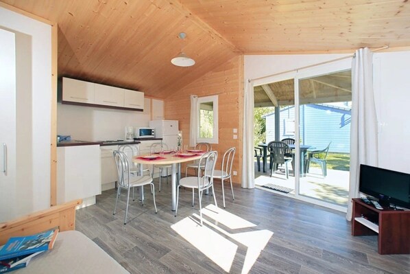 A compact kitchen with a dining area, a TV, and a sliding glass door leading to an outdoor patio.