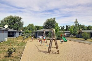 Un parque infantil con columpios y tobogán, rodeado de casas móviles.