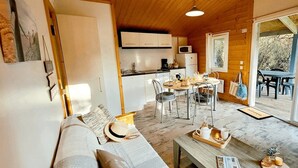 Ein gemütliches Blockhäuschen-Interieur mit Essbereich, Küche und einer Couch mit einem Tablett voller Frühstücksleckereien.